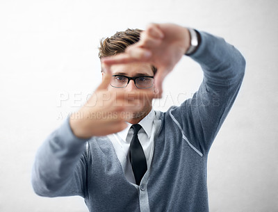 Buy stock photo A young and trendy guy wearing spectacles while making a frame with his fingers