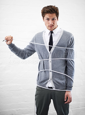 Buy stock photo A young nerdy guy with a cable wrapped around him