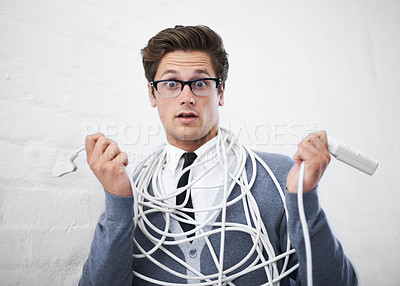 Buy stock photo A young nerdy guy tangled up in cables