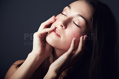 Buy stock photo Woman, hands on face and natural beauty with skincare, cosmetics and wellness on dark background. Model touching skin, makeup and posing with eyes closed for dermatology shine or glow in studio 