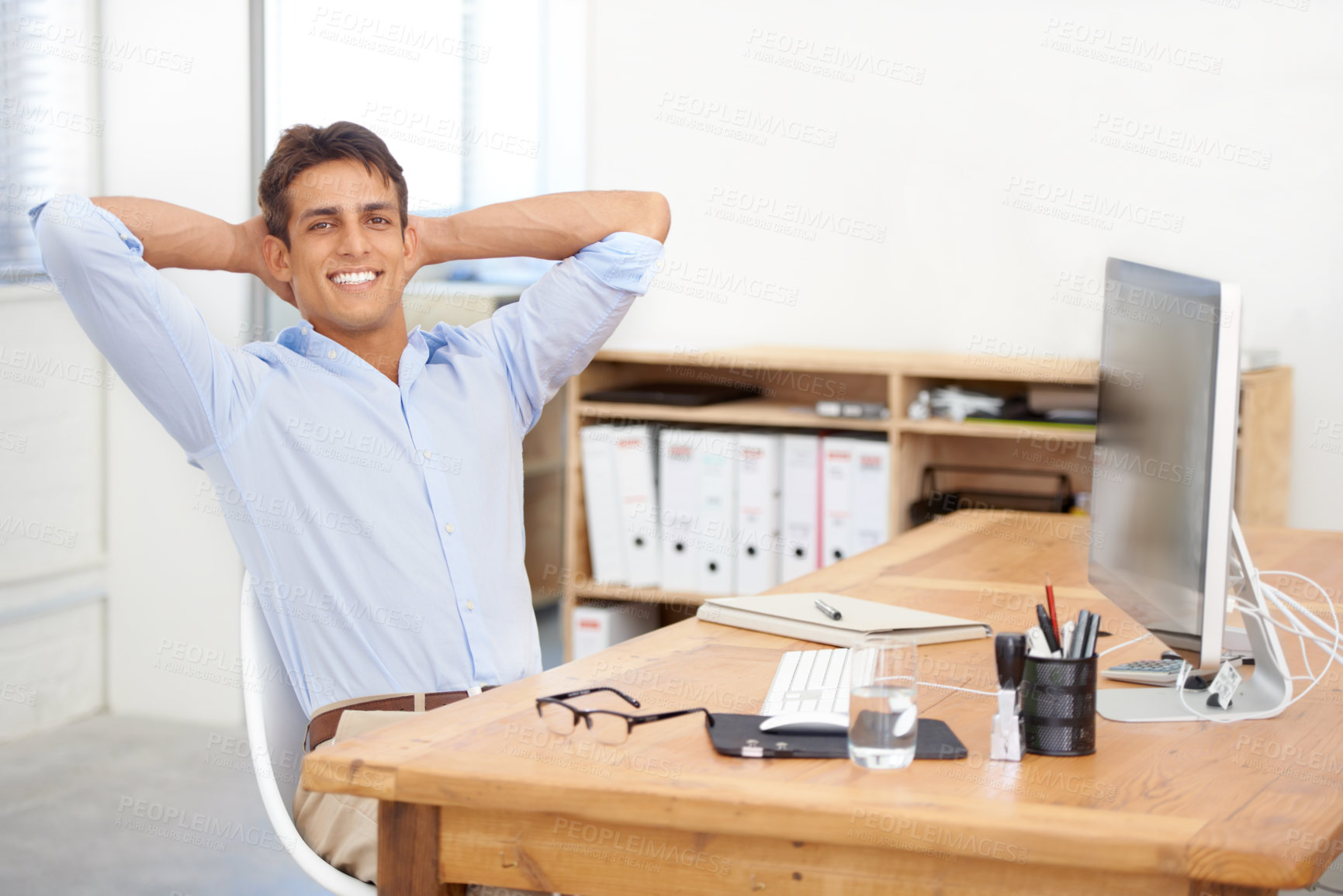 Buy stock photo Portrait, relax or happy man in office resting on break for mental health, pride or wellness at desk. Calm, freedom or employee with smile or hand behind his head in a business stretching or resting