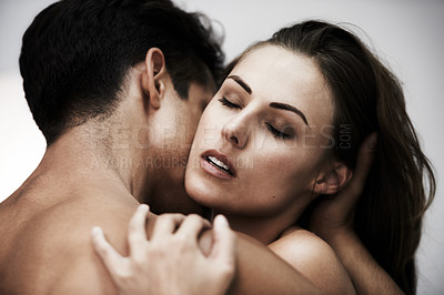 Buy stock photo Studio shot of a young couple sharing an intimate moment against a gray background