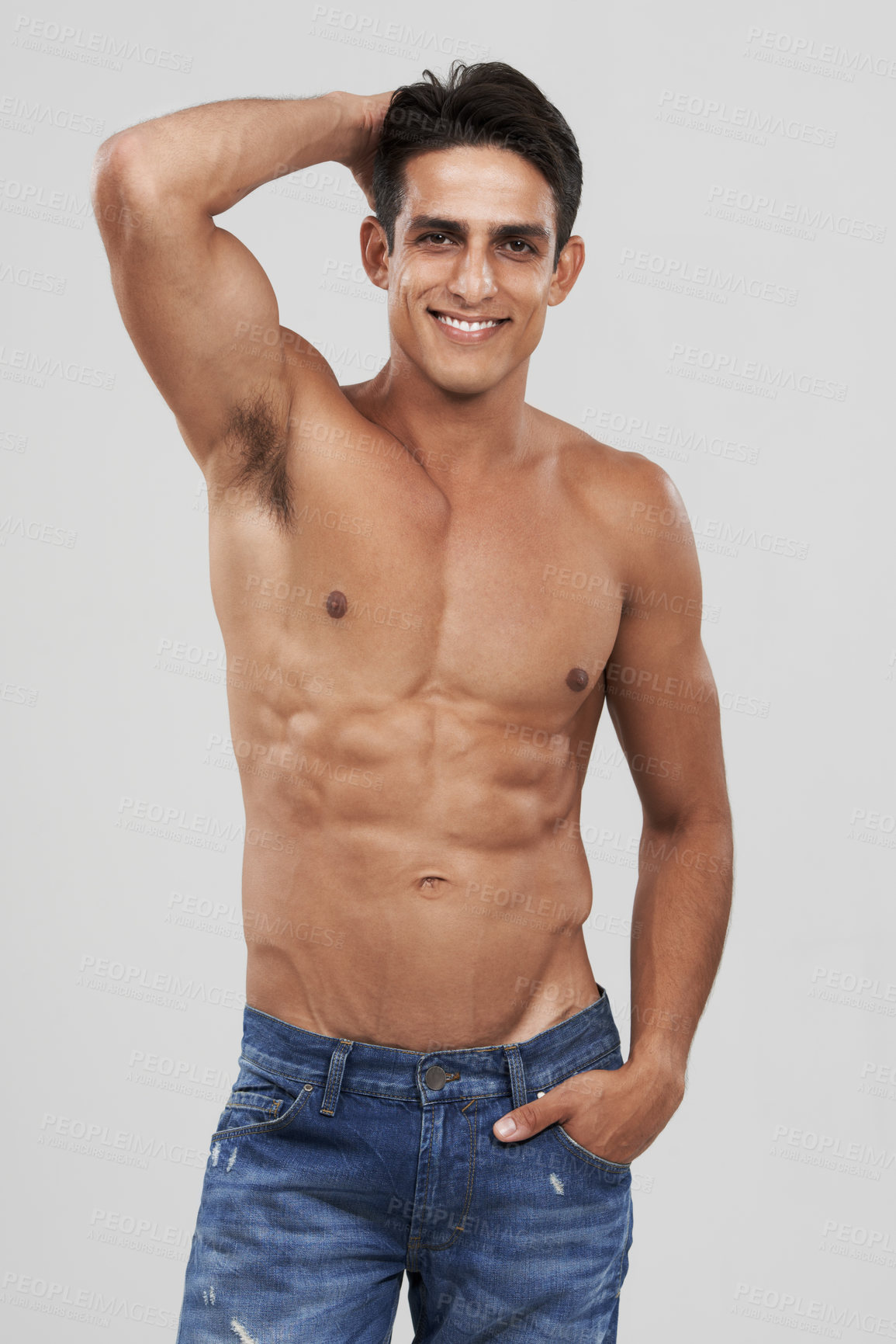 Buy stock photo Man, portrait and smile in studio for fashion, confidence and bodybuilder in jeans for style. Male person, shirtless and fitness or muscle progress, face and body care or wellness by gray background