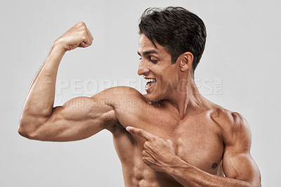 Buy stock photo An isolated shot of a macho and muscular man pulling his bicep to show off 