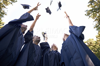 Buy stock photo A group of college graduates celebrating by throwing their hats in the sky