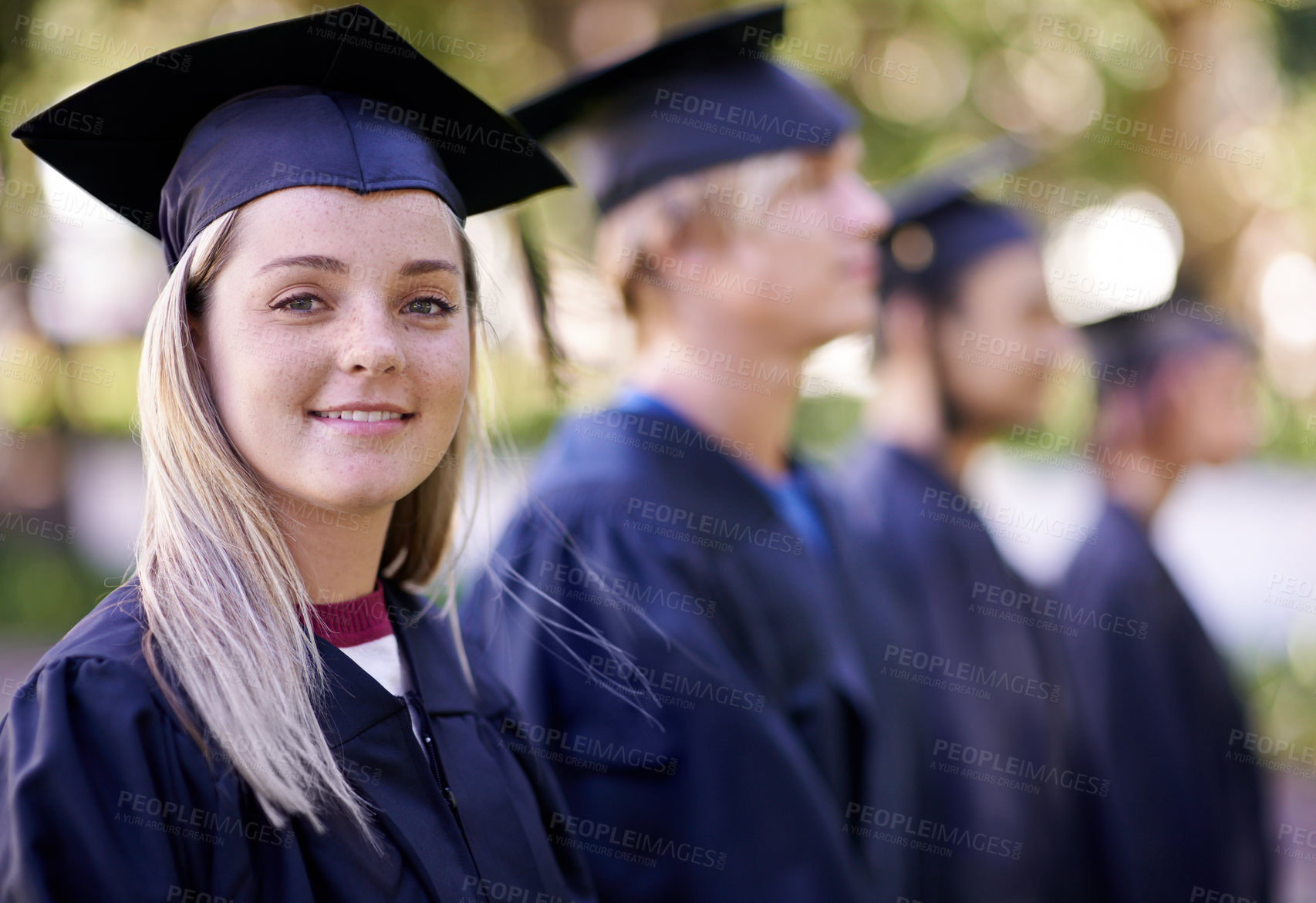 Buy stock photo Portrait of a happy graduate standing in a row with her peers waiting for her diploma