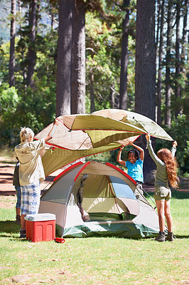 Buy stock photo Children, tent and camping setup in forest for shelter, cover together on the grass in nature. Happy kids in teamwork setting up tents for camp adventure or holiday vacation in the woods