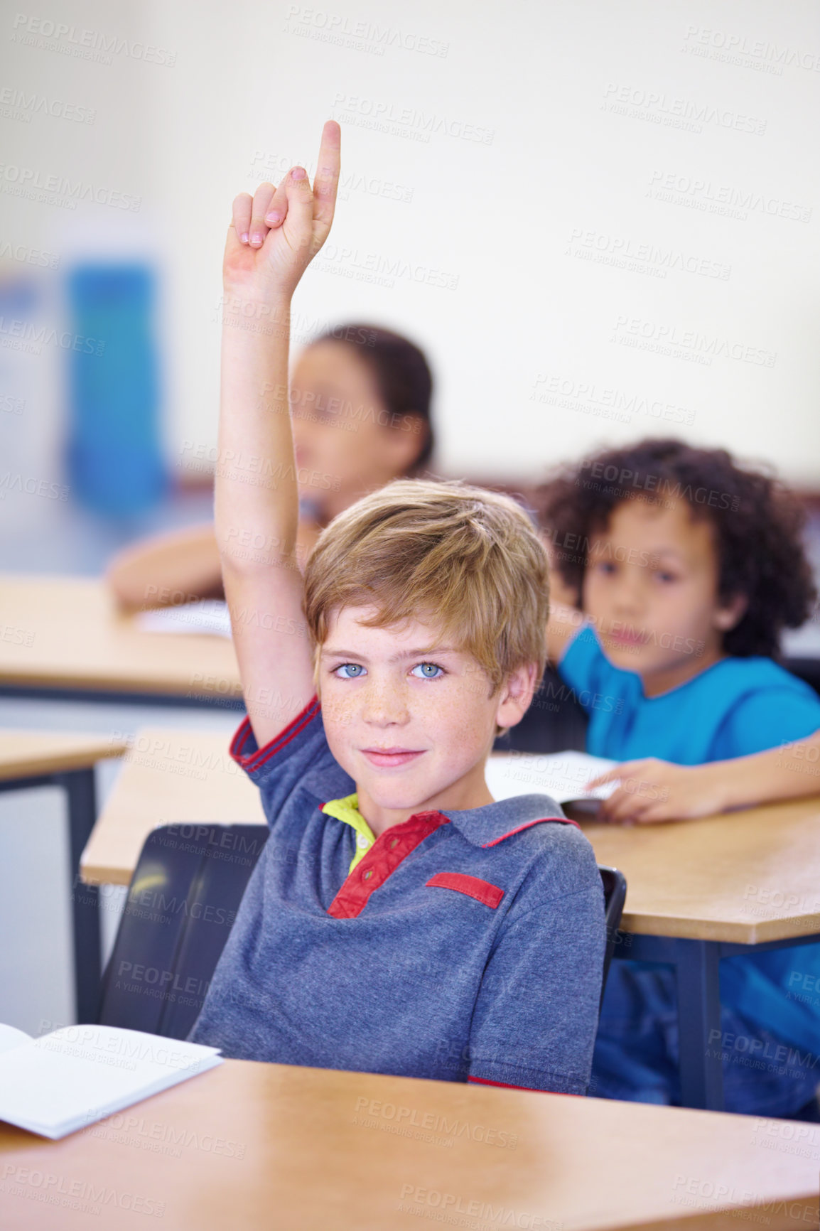 Buy stock photo Portrait of a young boy holding his hand up in class to answer a question