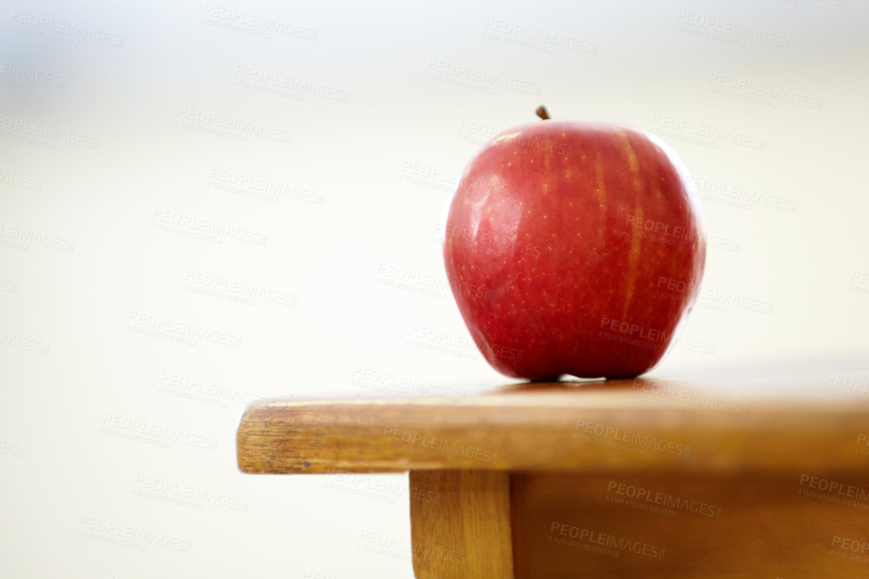 Buy stock photo Red apple, desk and classroom for natural diet, snack or nutrition and fiber on table. Closeup of fresh organic fruit or food for eating, health and wellness on mockup space in empty class at school