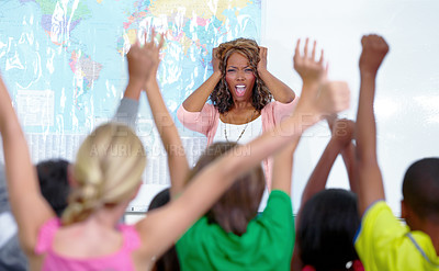 Buy stock photo A stressed out teacher covering her ears in front of her raucous classroom
