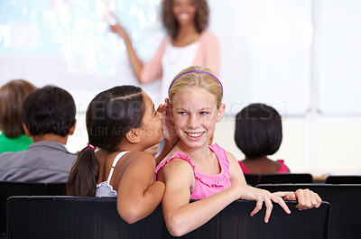 Buy stock photo Kids, classroom and whisper in ear for secret, gossip or communication in lesson at school. Little girl, students or friends listening to rumor, information or surprise in class together with teacher