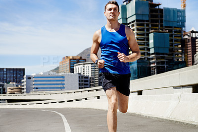 Buy stock photo Young man keeping fit by going for a run in the city