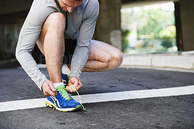 Buy stock photo Cropped shot of a young man tying his laces before a run