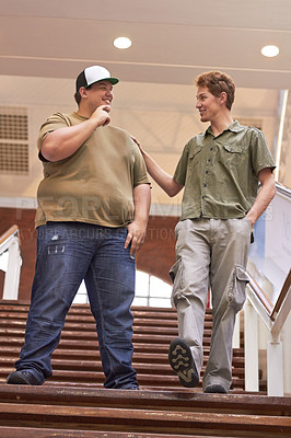 Buy stock photo Student, teenager friends and boys walking down university and school steps with a smile. Conversation, talking and discussion of guy group feeing happy on education building stairs with a talk