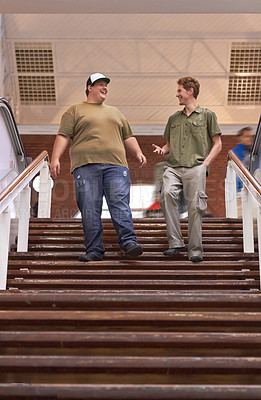 Buy stock photo Student, teenager friends and campus boys walking down university and school steps with a smile. Conversation, talking and discussion of guy group feeling happy on education building stairs with talk