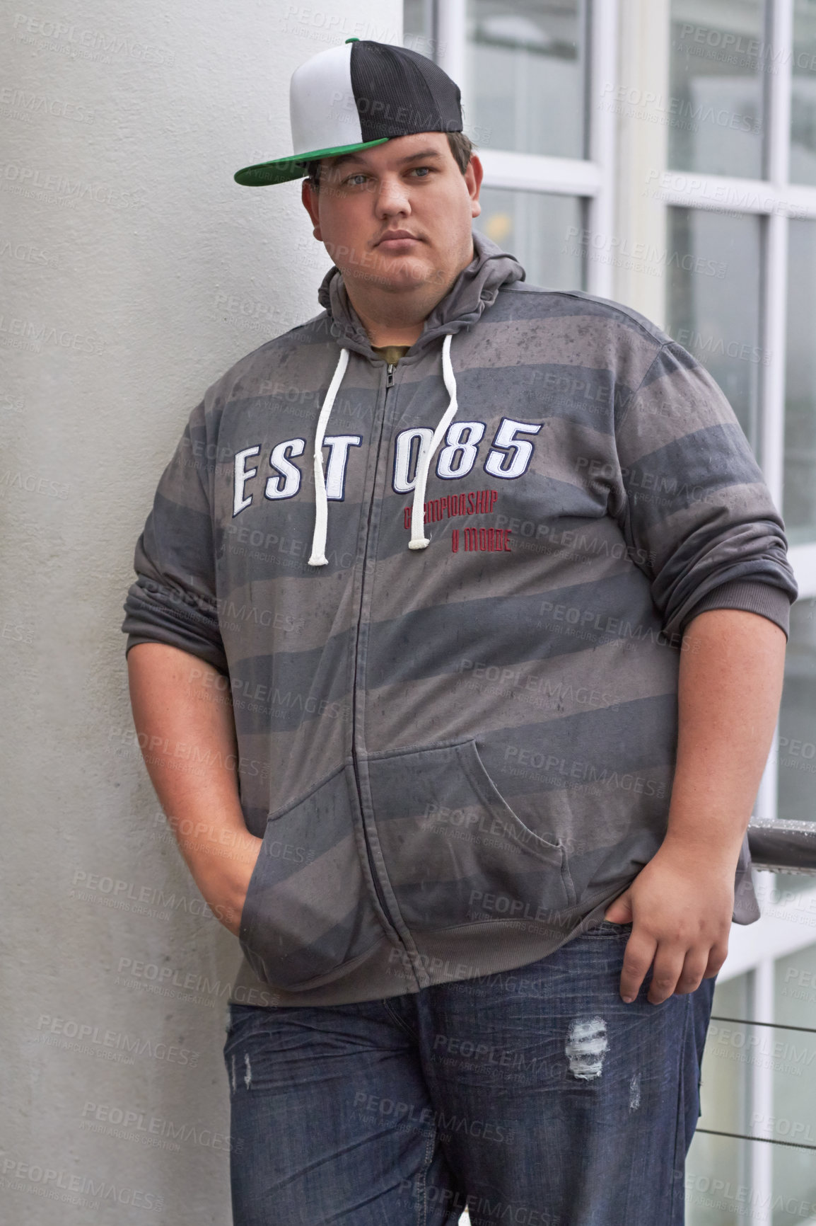 Buy stock photo Portrait of young man leaning against a wall while standing outside