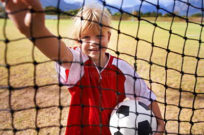 Buy stock photo Girl, soccer player and ball on goal net, smile and happy for game, field and child. Outdoor, playful and sport for childhood, portrait and athlete for match, alone and outside on football pitch