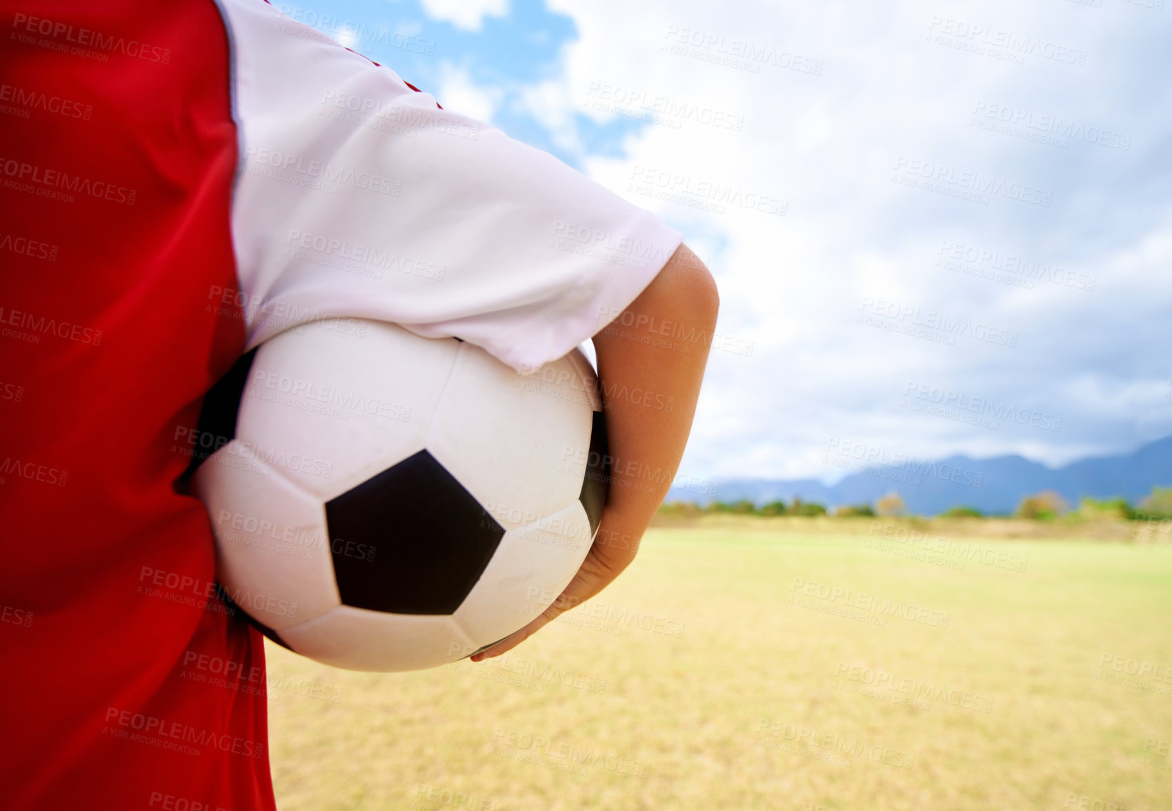 Buy stock photo Child, arm and soccer ball on green grass for sports, training or practice in cloudy blue sky. Closeup of football player, athlete or kid ready for kick off, game or match on outdoor field in nature