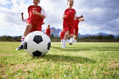 Buy stock photo Running, closeup and sports with children and soccer ball on field for training, competition and fitness. Teamwork, summer and action with football player on pitch for goals, energy and kids game