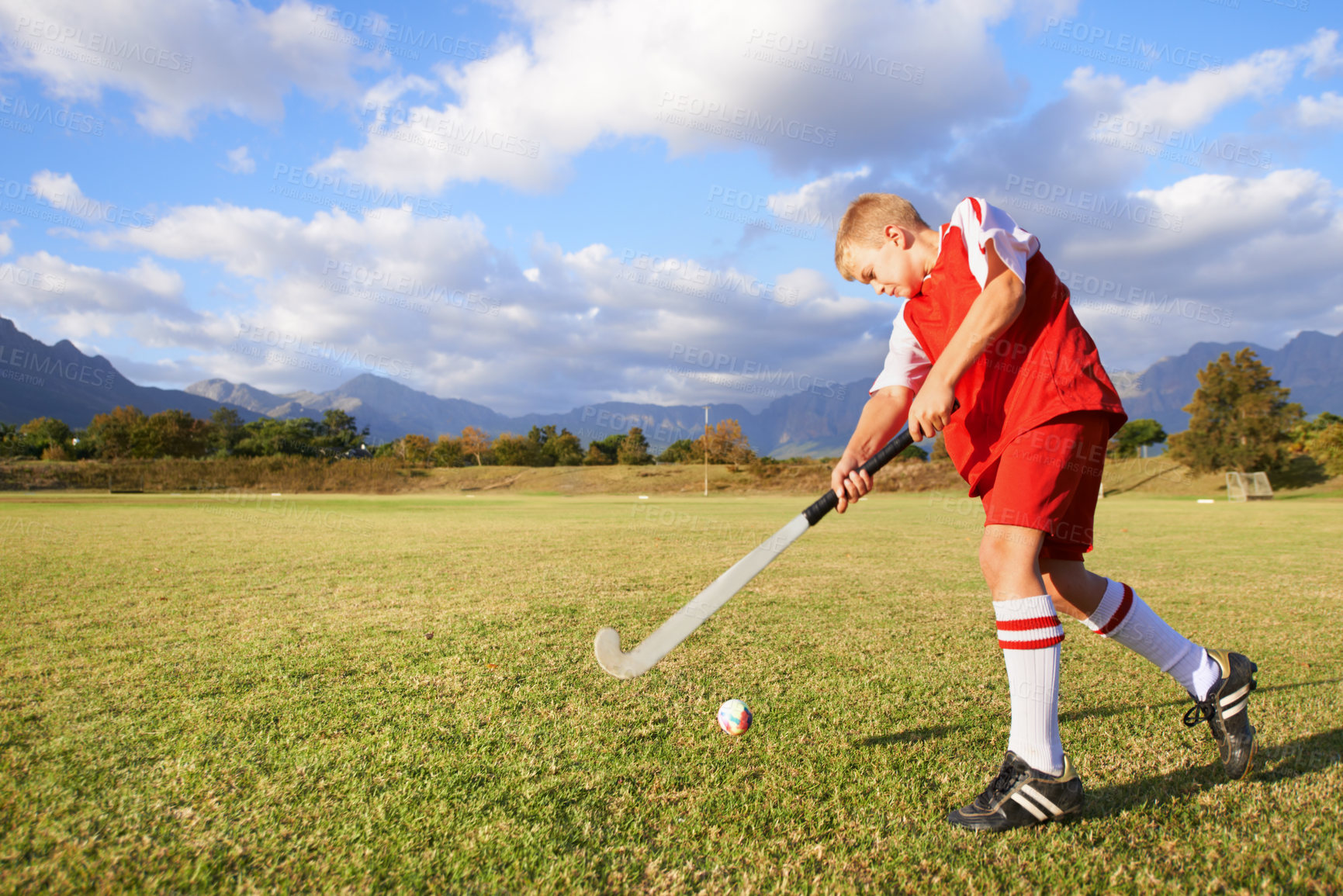 Buy stock photo Child, ball and hockey on field for sports, outdoor practice match or game in nature. Young kid or teen player enjoying day on green grass with stick for fitness, activity or training with blue sky