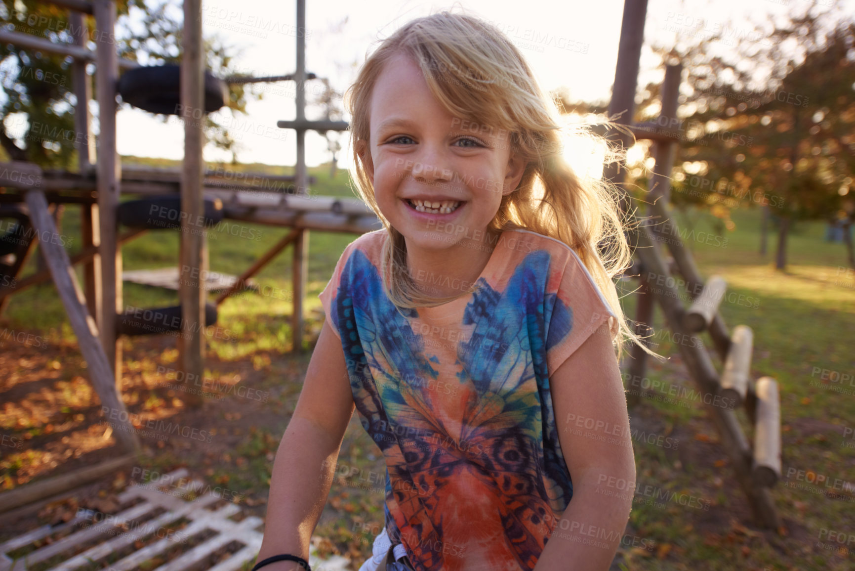 Buy stock photo Happy girl, portrait and playing in park with sunset for fun holiday, weekend or outdoor break in nature. Face of female person, kid or child smile on playground for childhood activity outside