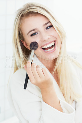 Buy stock photo A gorgeous young woman in her bathrobe applying blusher