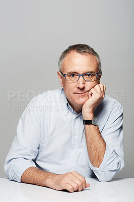 Buy stock photo Bored, portrait and senior businessman in a studio with pride for legal corporate career. Glasses, table and professional elderly male lawyer with tired face expression isolated by gray background.