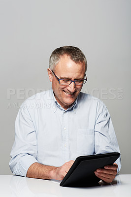 Buy stock photo Studio shot of a mature man working on a digital tablet