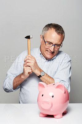 Buy stock photo Studio shot of a mature man about to break open a piggybank with a hammer