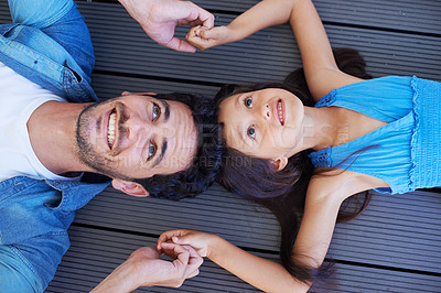 Buy stock photo Holding hands, top view and relax father, happy kid or family bonding together for trust, support and solidarity. Fathers Day, floor and face of young kid, youth girl and dad lying on ground