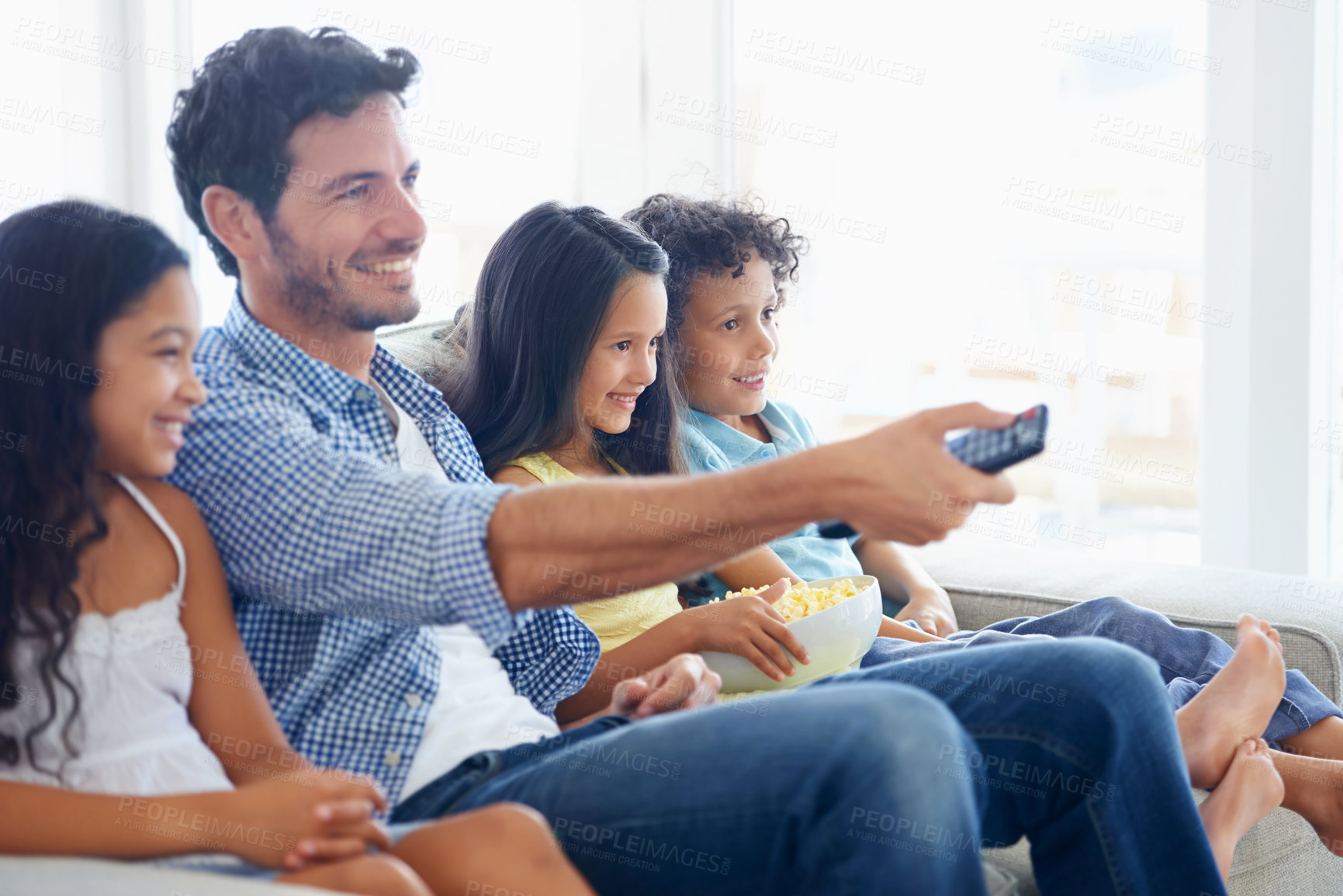 Buy stock photo Shot of a family eating popcorn while sitting on a sofa and watching tv