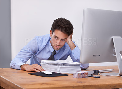 Buy stock photo Shot of a tired looking office worker sitting at his desk