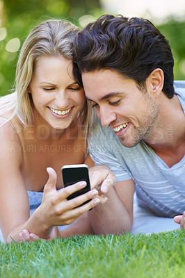 Buy stock photo Grass, phone or happy couple on social media in nature to relax together on outdoor holiday vacation. Smile, woman or man with funny meme or online post for bond with love, support or care on field