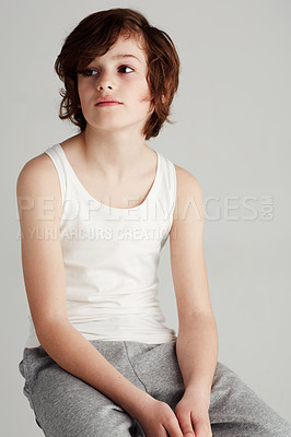 Buy stock photo A young boy sitting on a stool in the studio while looking away