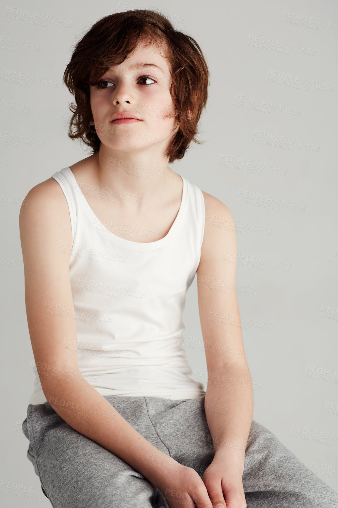 Buy stock photo A young boy sitting on a stool in the studio while looking away