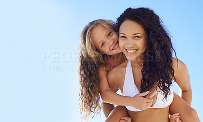 Buy stock photo A young mother carrying her daughter on her back on the beach