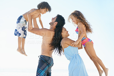Buy stock photo Happy family, beach and lifting children in bonding, vacation or outdoor holiday weekend together. Father, mother and child smile for love, support or summer by ocean coast with blue sky background