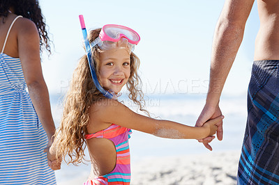 Buy stock photo Portrait of a cute little girl with snorkeling gear walking hand in hand with her parents at the beach
