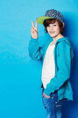 Buy stock photo Fashion, peace sign and portrait of a boy in a studio with a casual, trendy and cool outfit. Teenager, smile and happy boy kid model with hipster apparel style posing isolated by a blue background.