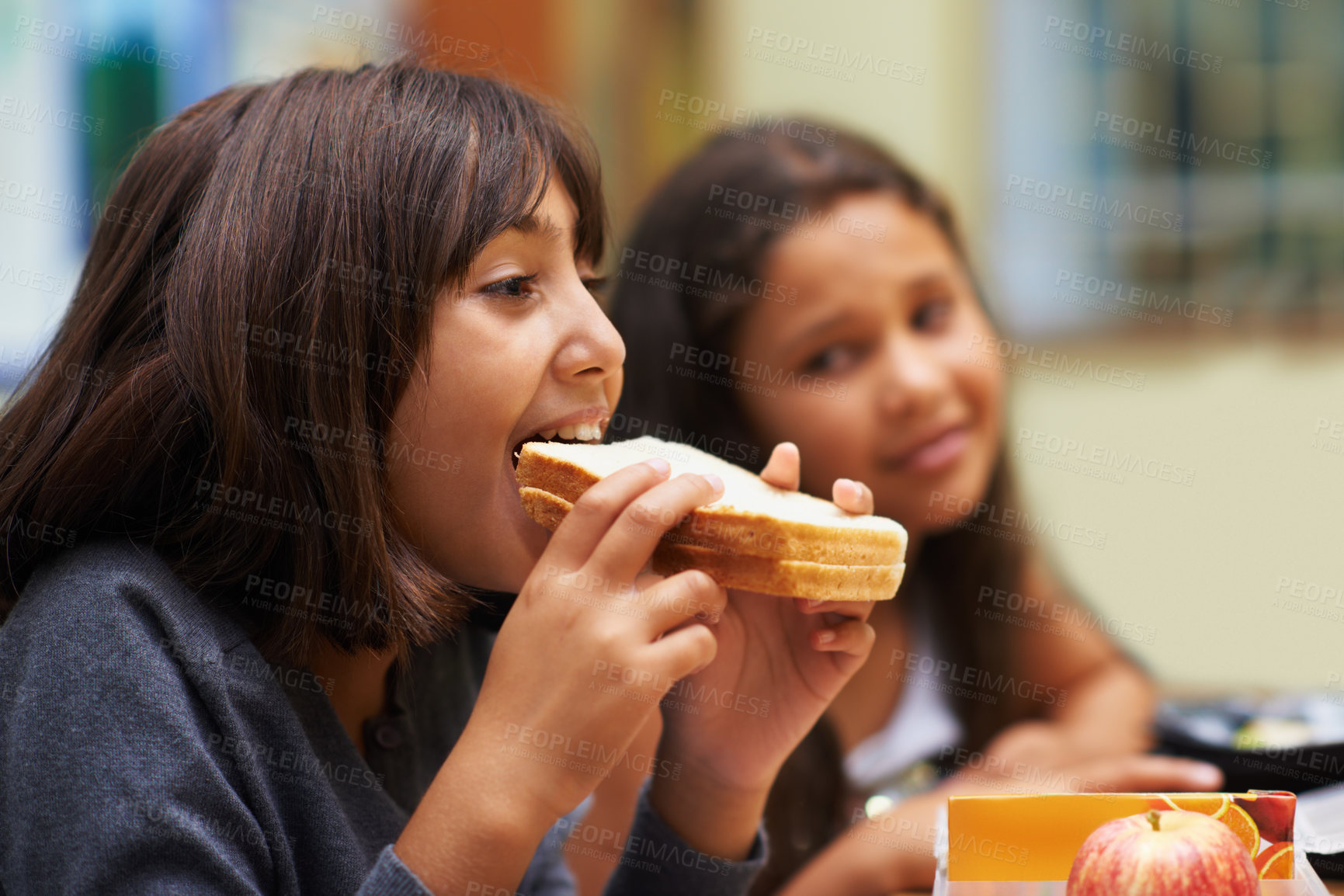 Buy stock photo Hungry girl, student and eating sandwich in classroom at school for meal, break or snack time. Young kid, person or elementary child biting bread for lunch, fiber or nutrition in class during recess