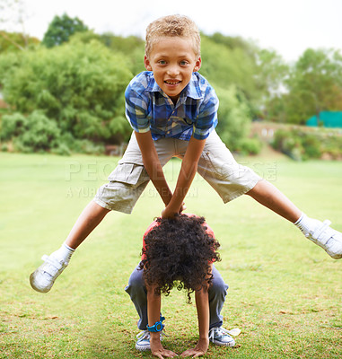 Buy stock photo A young boy doing a leapfrog over his friend's back