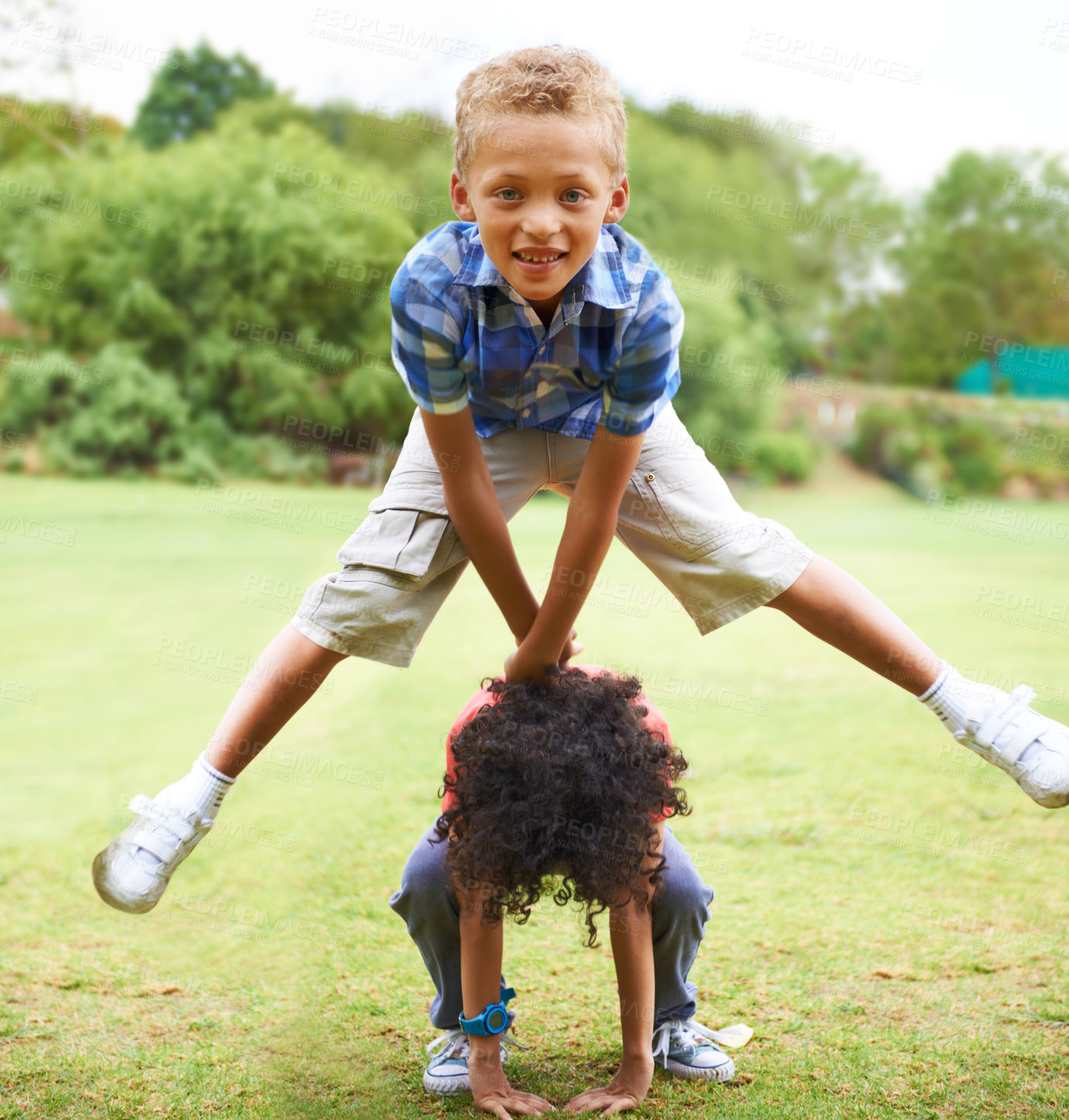 Buy stock photo A young boy doing a leapfrog over his friend's back