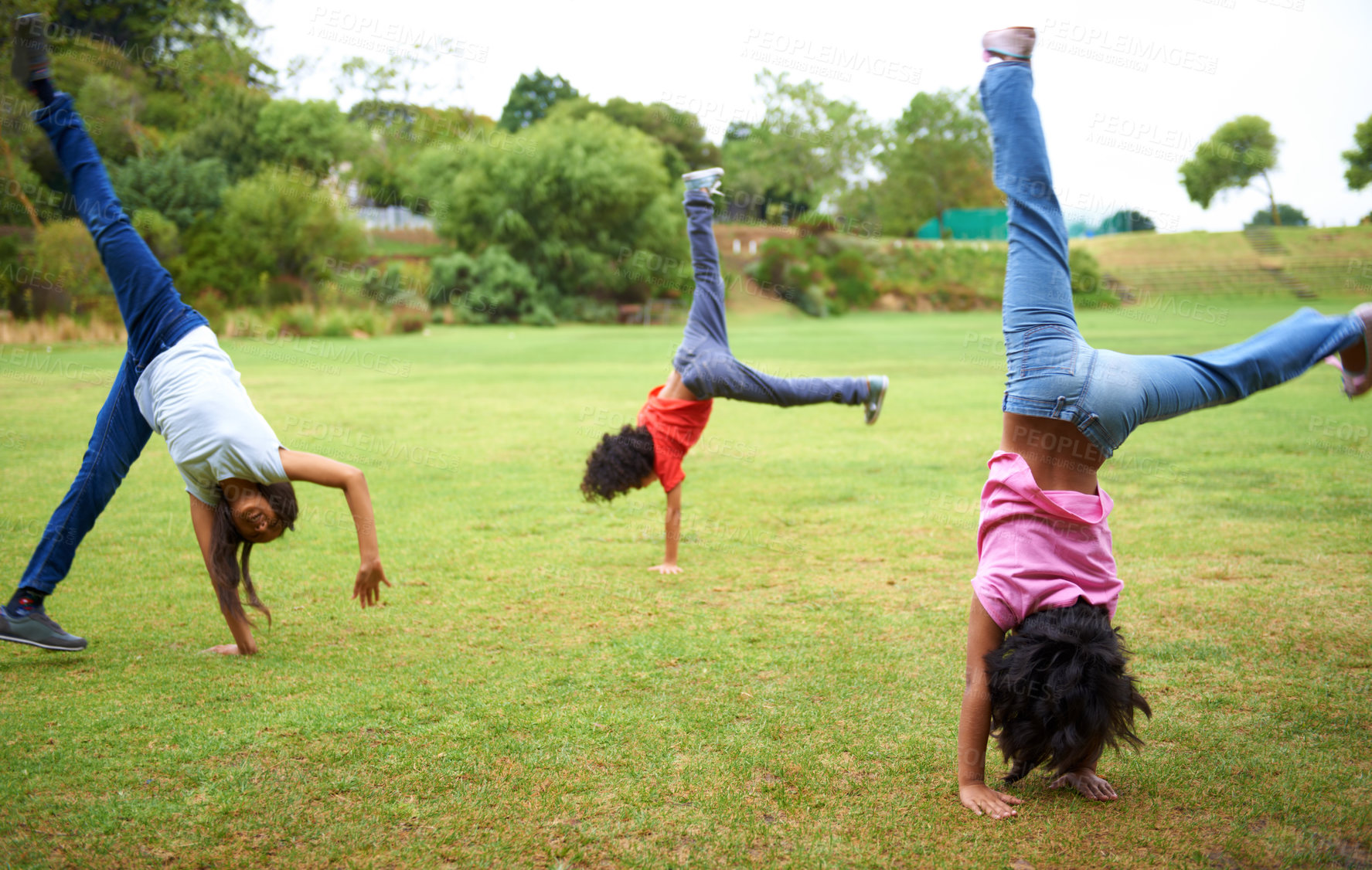 Buy stock photo Three young children doing handstands in the park