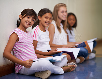 Buy stock photo Girl, students and portrait of friends with books sitting at school in hallway for education or learning. Group of young kids or children smile with textbooks on corridor floor outside classroom