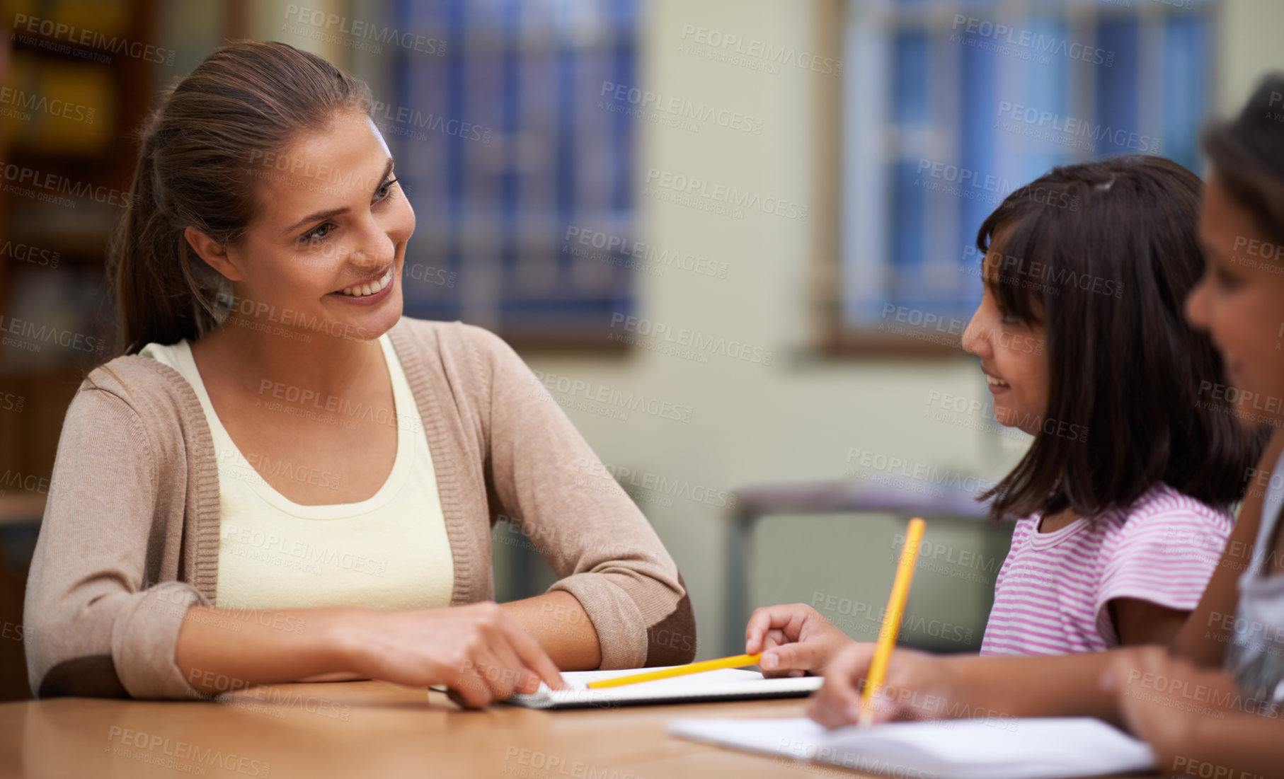 Buy stock photo Shot of a teacher helping her students with their work in the classroom