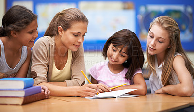 Buy stock photo Shot of a teacher helping her students with their work in the classroom