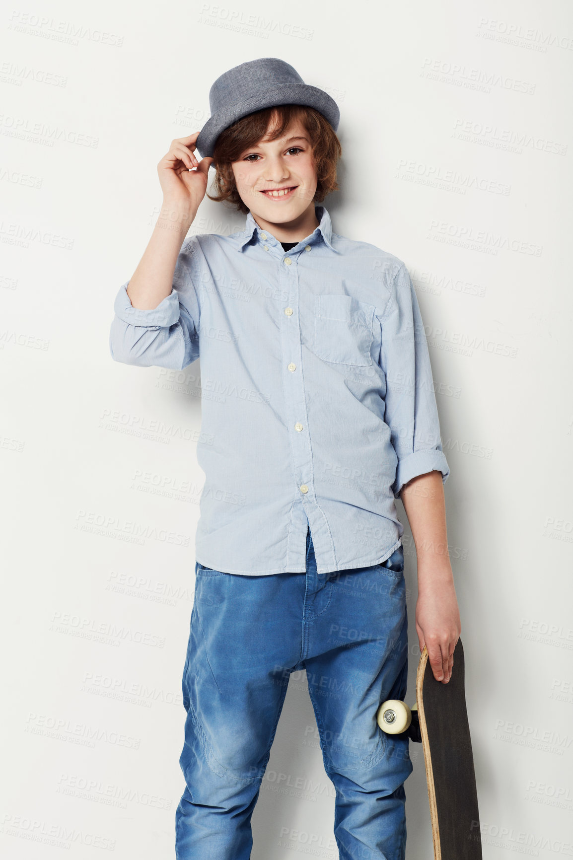 Buy stock photo Cute preteen boy wearing trendy attire and holding a skateboard while isolated on white