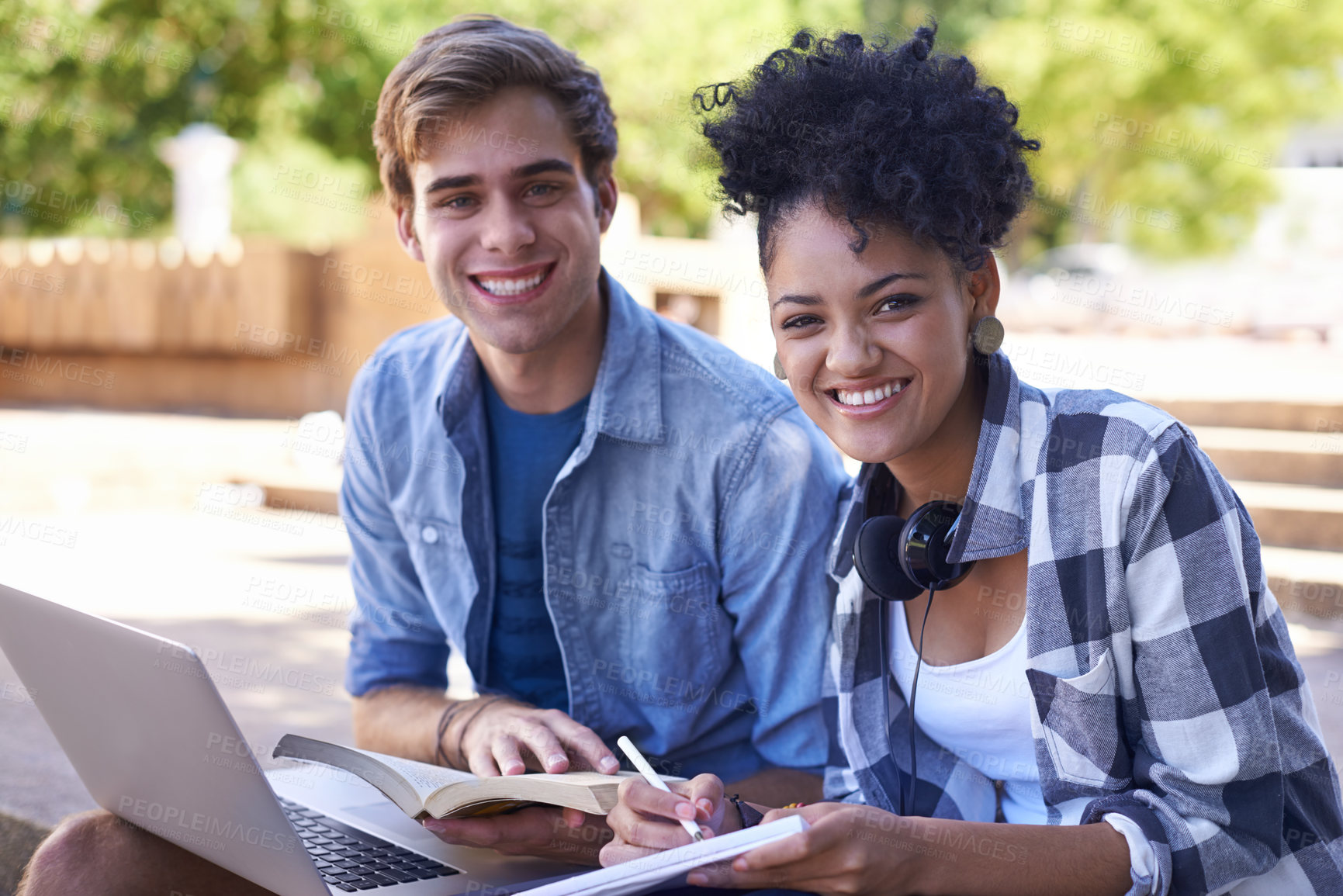 Buy stock photo Shot of two college students studying together on campus grounds