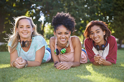 Buy stock photo Grass, portrait or women in park at college, campus or  together with community, smile or group. University, relax or happy students bond with support, headphones or diversity in education on field