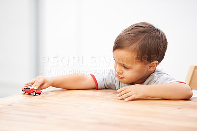 Buy stock photo Shot of a cute young boy playing with a toy car